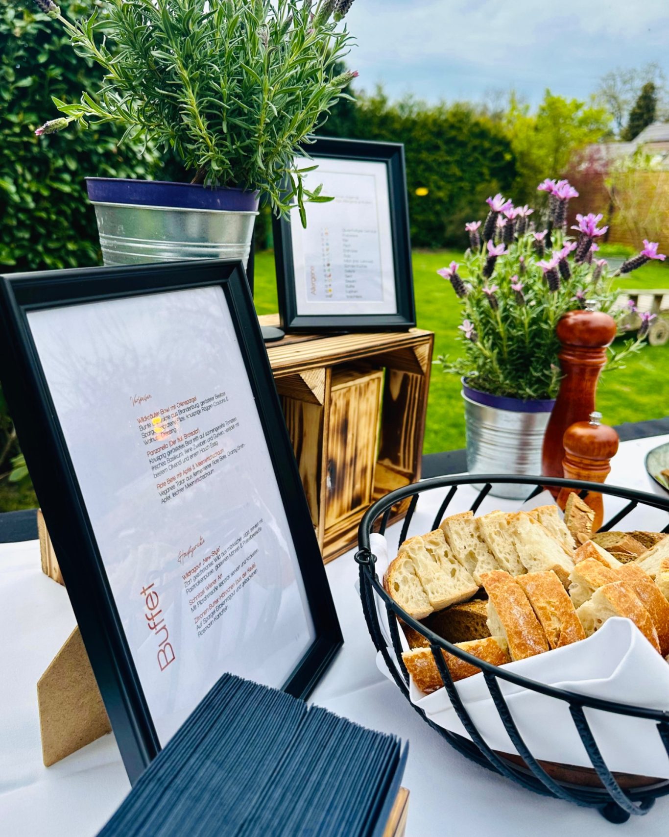 Gerahmte Buffet- und Allergenkarte neben Brotkorb und Lavendel auf weiß gedeckter Tafel
